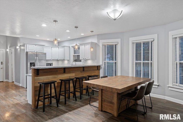 dining area featuring dark hardwood / wood-style flooring, sink, and a textured ceiling