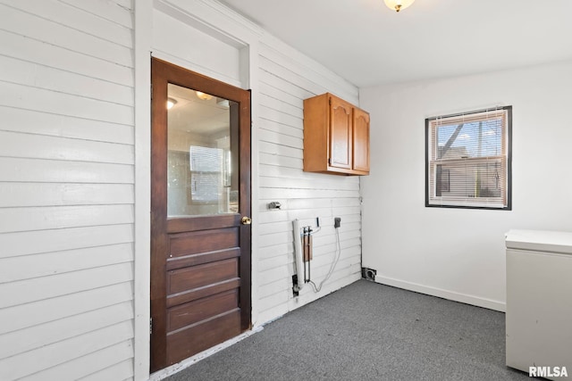 clothes washing area with cabinets and dark carpet