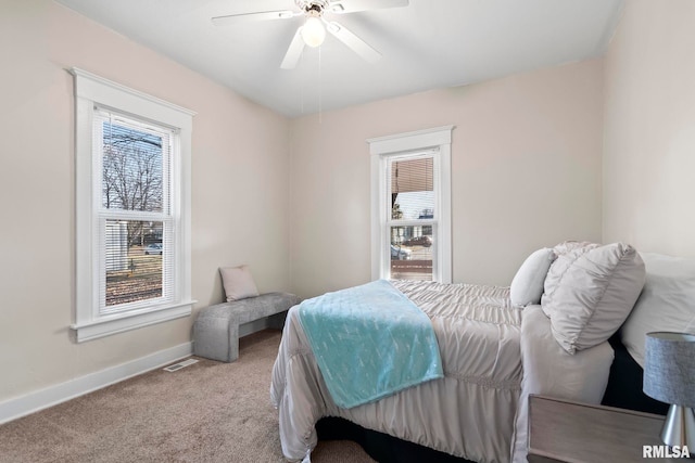 carpeted bedroom with multiple windows and ceiling fan