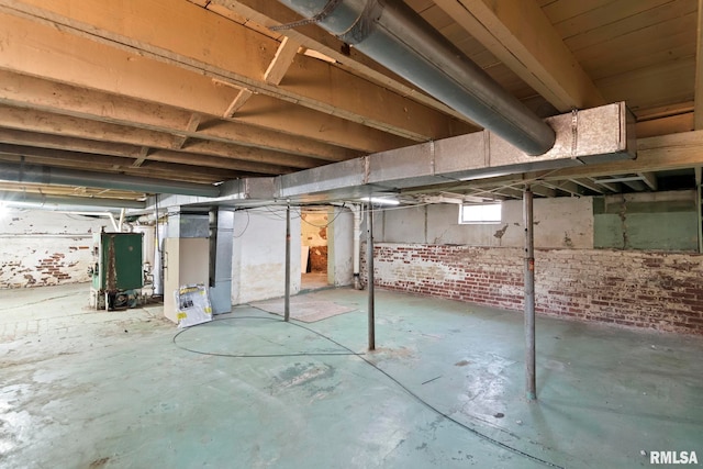 basement featuring brick wall and heating unit