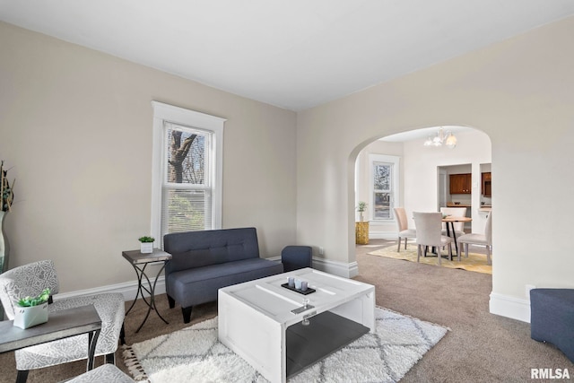 carpeted living room featuring an inviting chandelier