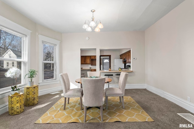 carpeted dining area featuring a chandelier