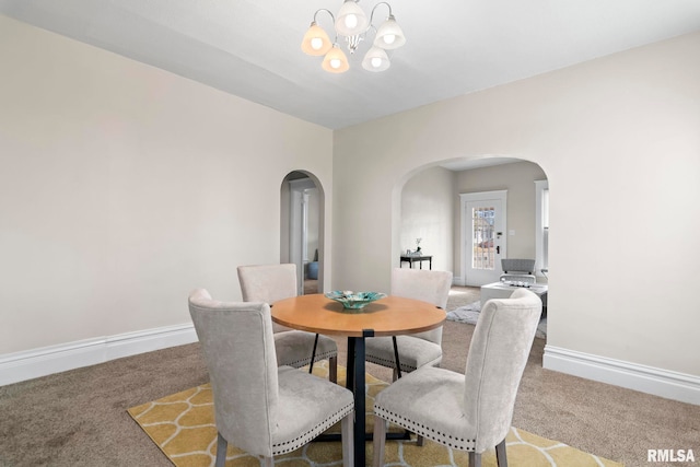 carpeted dining space featuring a notable chandelier