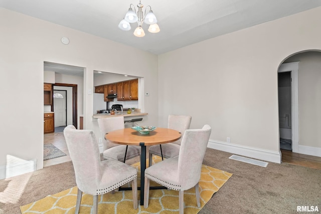 carpeted dining room with a chandelier