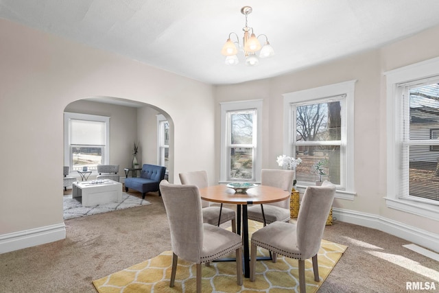 carpeted dining area featuring a notable chandelier