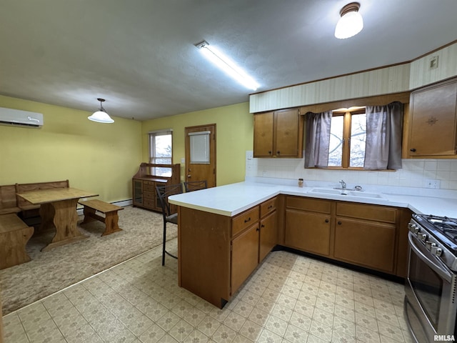 kitchen with kitchen peninsula, a wall mounted air conditioner, sink, stainless steel range with gas cooktop, and hanging light fixtures