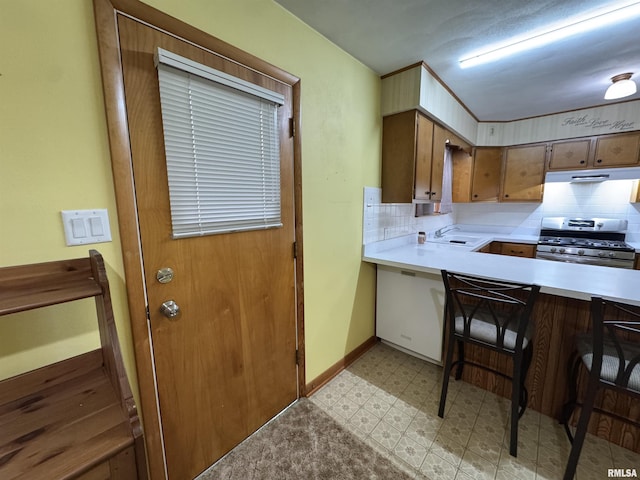 kitchen with a kitchen breakfast bar, decorative backsplash, stainless steel range with gas cooktop, and sink