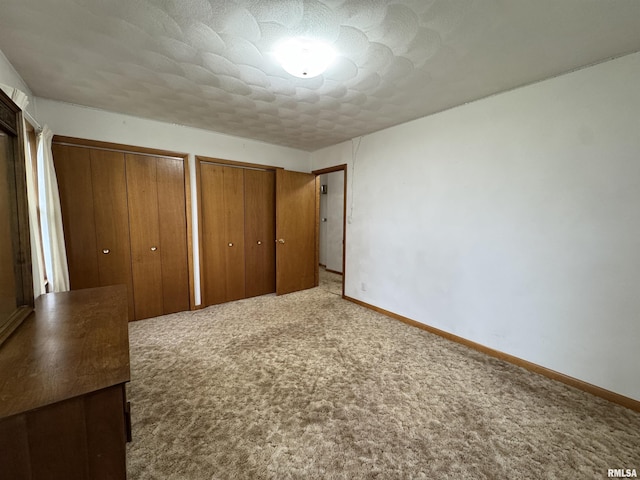 unfurnished bedroom with carpet floors and multiple closets