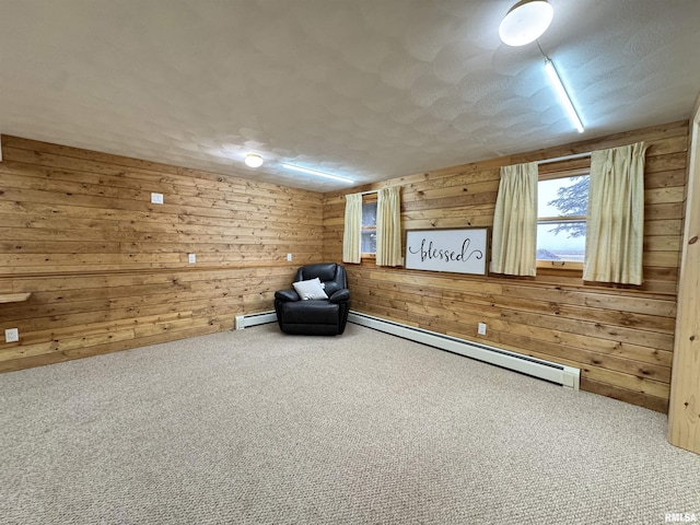 unfurnished room featuring carpet, wood walls, and a baseboard heating unit