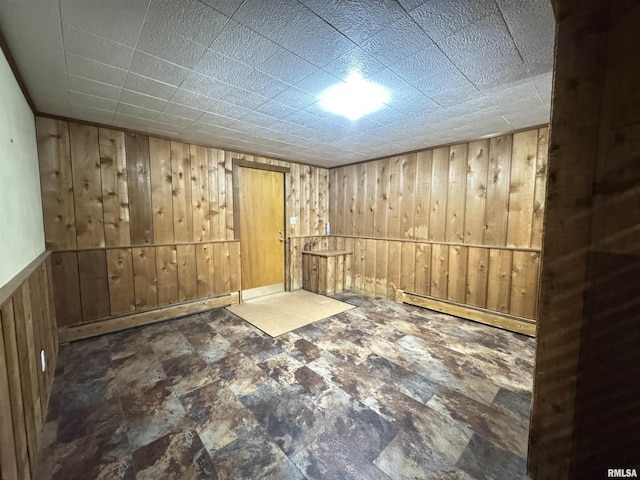 basement featuring wood walls and a baseboard radiator