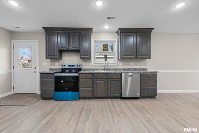 kitchen with dark brown cabinets, sink, light wood-type flooring, and stainless steel appliances