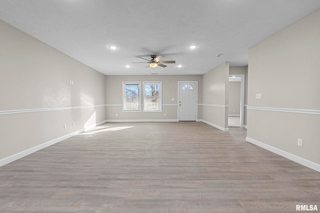 unfurnished living room with ceiling fan, light wood-type flooring, and a textured ceiling