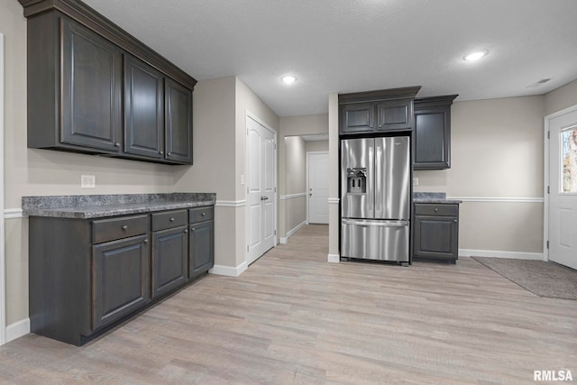 kitchen featuring stainless steel refrigerator with ice dispenser, a textured ceiling, and light hardwood / wood-style flooring