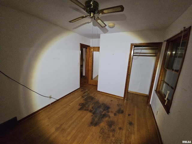 unfurnished bedroom with ceiling fan, dark wood-type flooring, and a closet