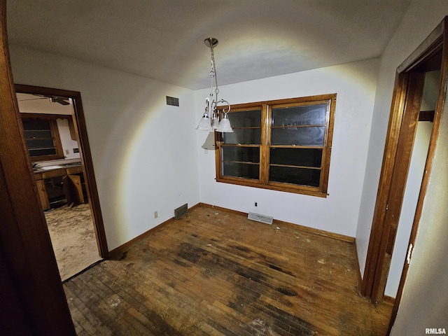 unfurnished dining area featuring a notable chandelier and dark wood-type flooring