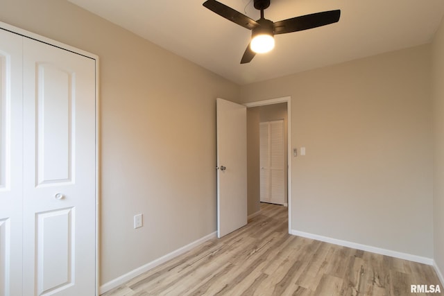 unfurnished bedroom with ceiling fan, light wood-type flooring, and a closet