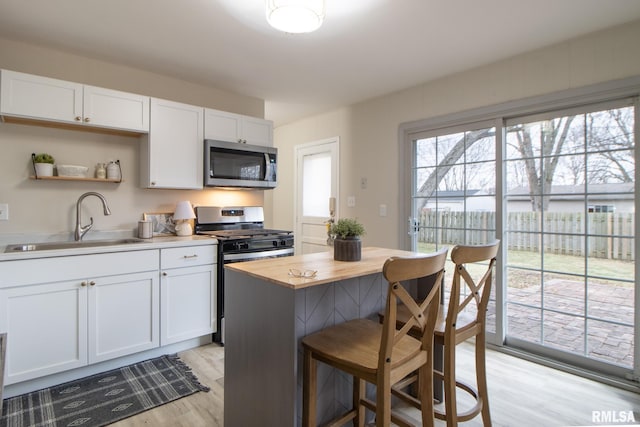 kitchen featuring sink, white cabinetry, stainless steel appliances, and light wood-type flooring