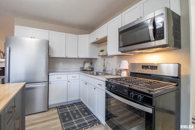 kitchen featuring gray cabinetry, stainless steel appliances, sink, light hardwood / wood-style floors, and white cabinetry