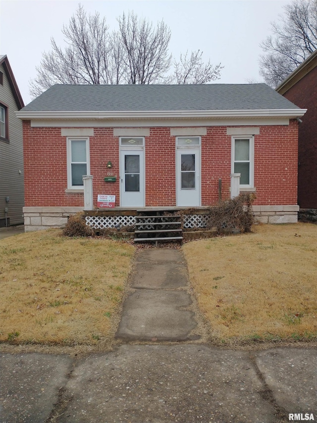 view of front of home with entry steps, brick siding, and a front lawn