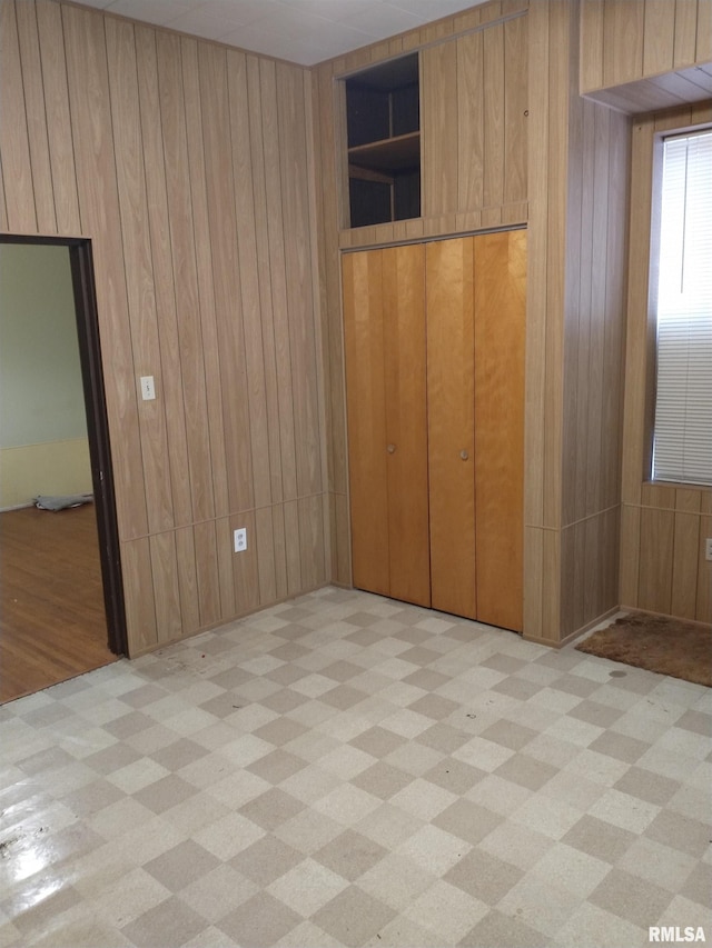 unfurnished bedroom with wooden walls and a closet