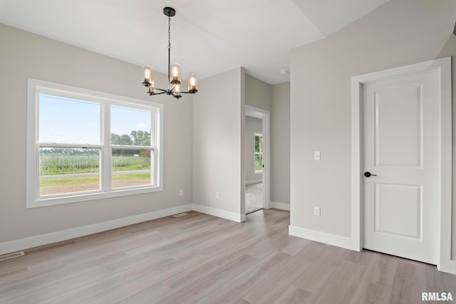 empty room featuring a chandelier and light wood-type flooring