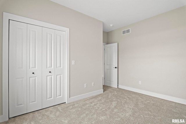 unfurnished bedroom featuring a closet and light colored carpet