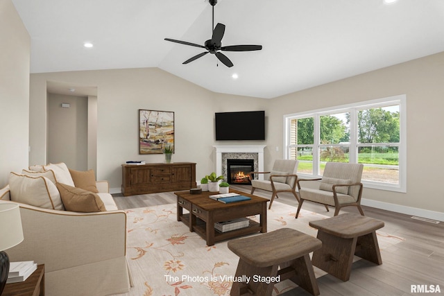 living room with ceiling fan, vaulted ceiling, and light wood-type flooring