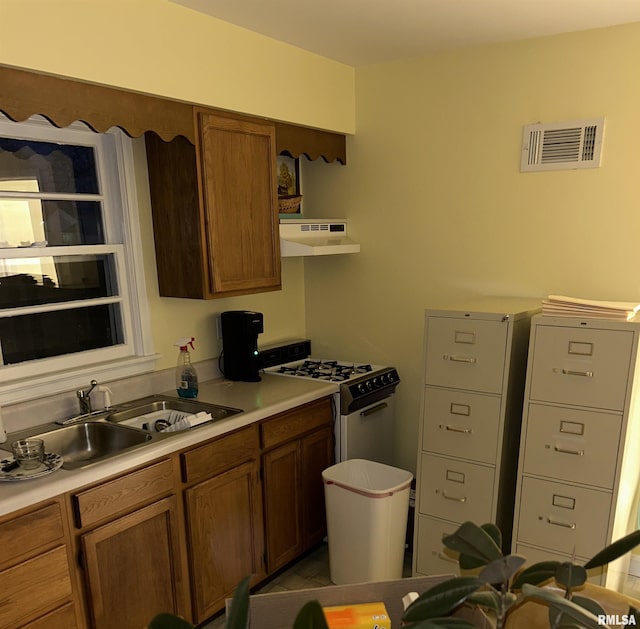 kitchen with white range oven, sink, and ventilation hood