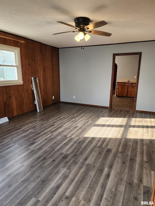 empty room featuring ceiling fan, wood walls, and dark hardwood / wood-style floors