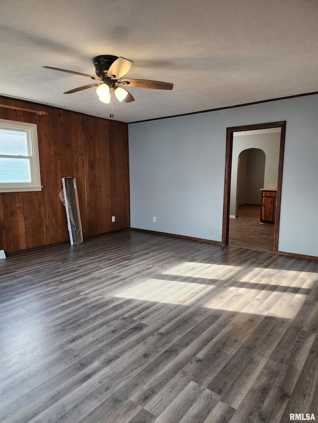 unfurnished room with wooden walls, hardwood / wood-style floors, ceiling fan, and a textured ceiling