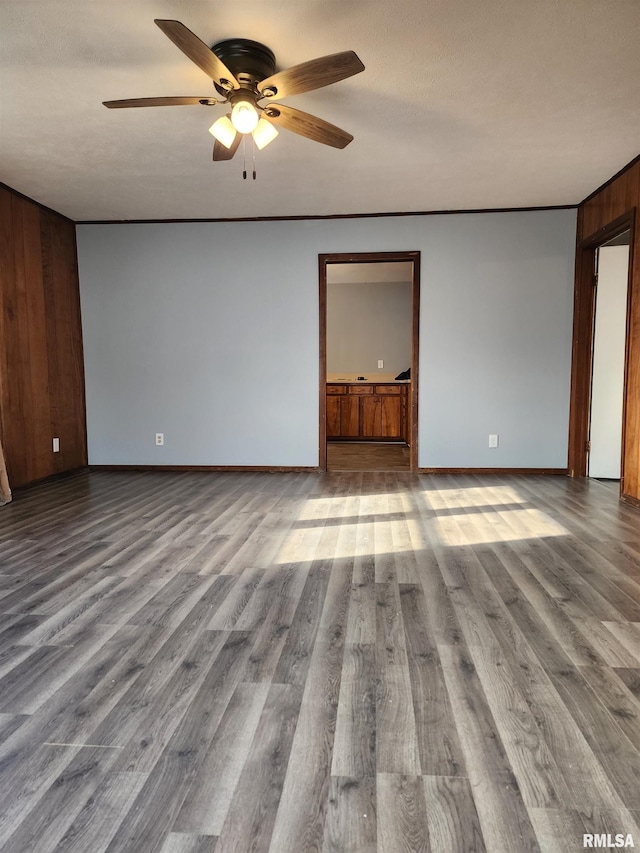 unfurnished room featuring hardwood / wood-style flooring, ceiling fan, and wood walls