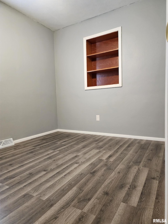 unfurnished room featuring built in shelves and dark hardwood / wood-style floors