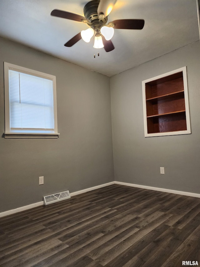 unfurnished room with built in shelves, ceiling fan, and dark hardwood / wood-style floors