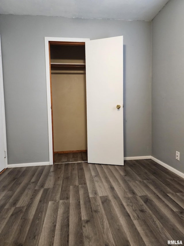 unfurnished bedroom with a closet and dark wood-type flooring