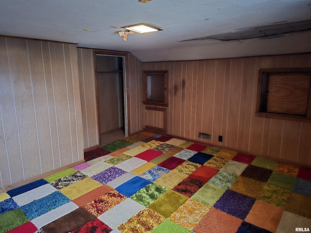 basement featuring wooden walls and light colored carpet