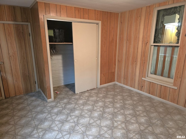 unfurnished bedroom featuring wood walls and a closet