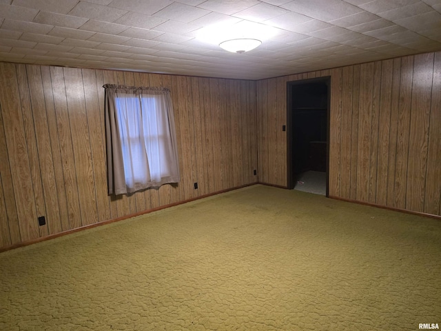 carpeted spare room featuring wood walls