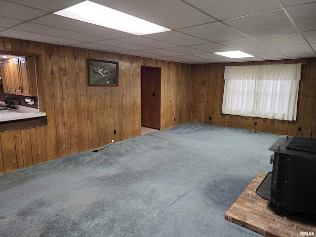 basement featuring carpet, a wood stove, and wooden walls