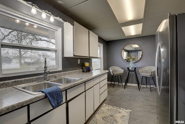 kitchen featuring white cabinets, stainless steel fridge, and sink