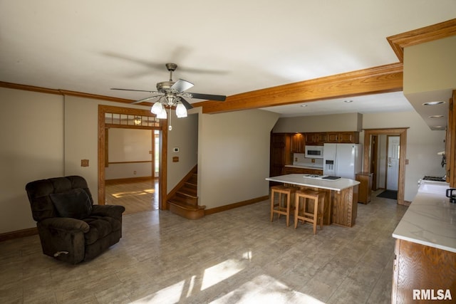 kitchen with white appliances, ceiling fan, ornamental molding, a kitchen island, and a kitchen bar