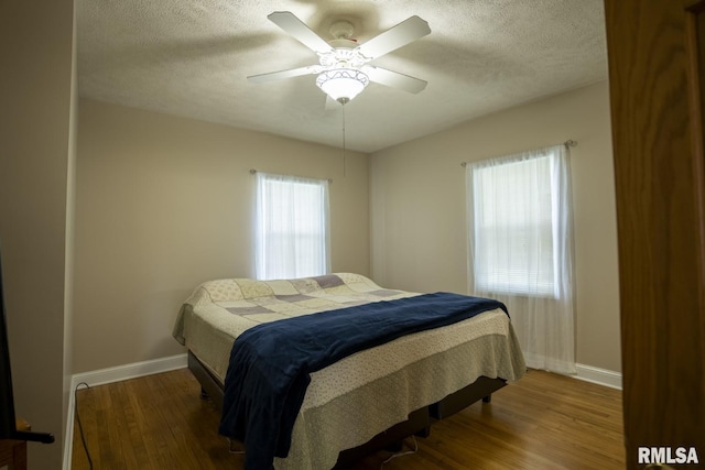 bedroom with ceiling fan, wood-type flooring, and a textured ceiling