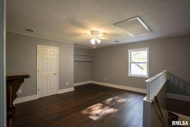 interior space with a textured ceiling, ceiling fan, ornamental molding, and dark wood-type flooring