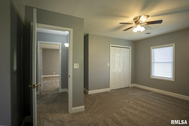 unfurnished bedroom featuring a textured ceiling, a closet, dark carpet, and ceiling fan