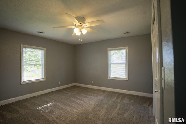 carpeted spare room featuring plenty of natural light and ceiling fan