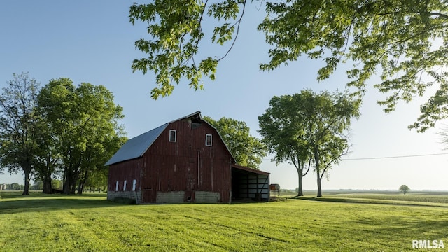 view of side of home with a lawn, a rural view, and an outdoor structure