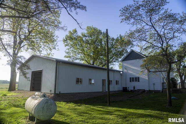 view of side of property with central air condition unit, a yard, an outdoor structure, and a garage