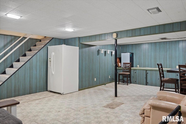 basement featuring white refrigerator with ice dispenser