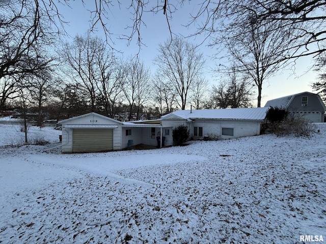 snow covered rear of property featuring a garage