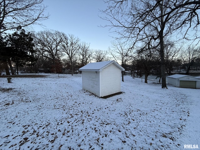 snow covered structure with a shed and an outbuilding