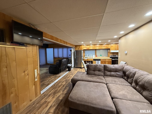 living room with wood walls, a paneled ceiling, wood-type flooring, and sink